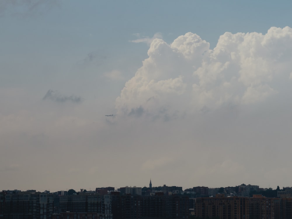 a plane flying over a city under a cloudy sky