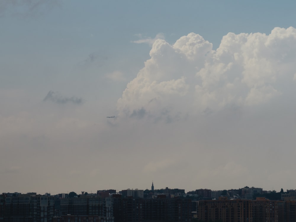 Un avión sobrevolando una ciudad bajo un cielo nublado