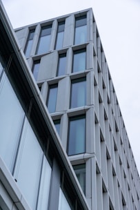 A modern building with an angular design featured by large windows and a sleek facade, showcasing a minimalist architectural style.