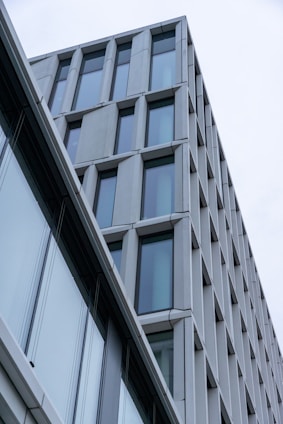 A modern building with an angular design featured by large windows and a sleek facade, showcasing a minimalist architectural style.