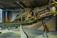 An old warplane resting in a museum hangar, bathed in soft natural light highlighting its worn paint.