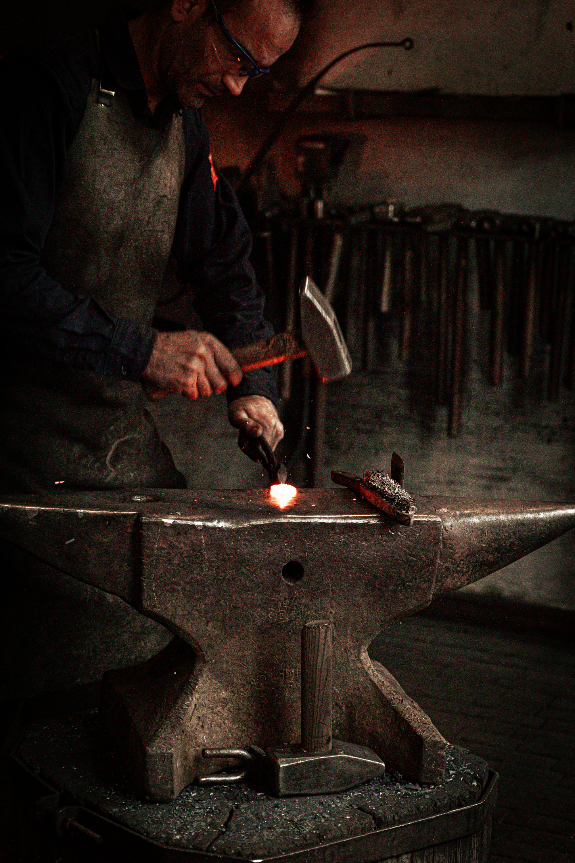 Artisan métallier travaillant une pièce au marteau sur son établi