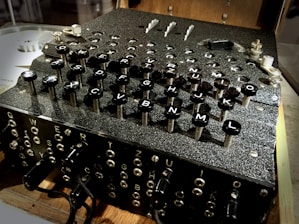 A vintage cipher machine with a complex array of keys labeled with letters. The machine's design suggests intricate mechanical components and historical significance.