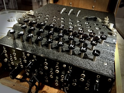 A vintage cipher machine with a complex array of keys labeled with letters. The machine's design suggests intricate mechanical components and historical significance.