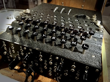 A vintage cipher machine with a complex array of keys labeled with letters. The machine's design suggests intricate mechanical components and historical significance.
