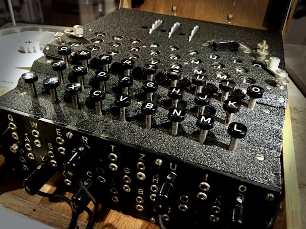 A vintage cipher machine with a complex array of keys labeled with letters. The machine's design suggests intricate mechanical components and historical significance.