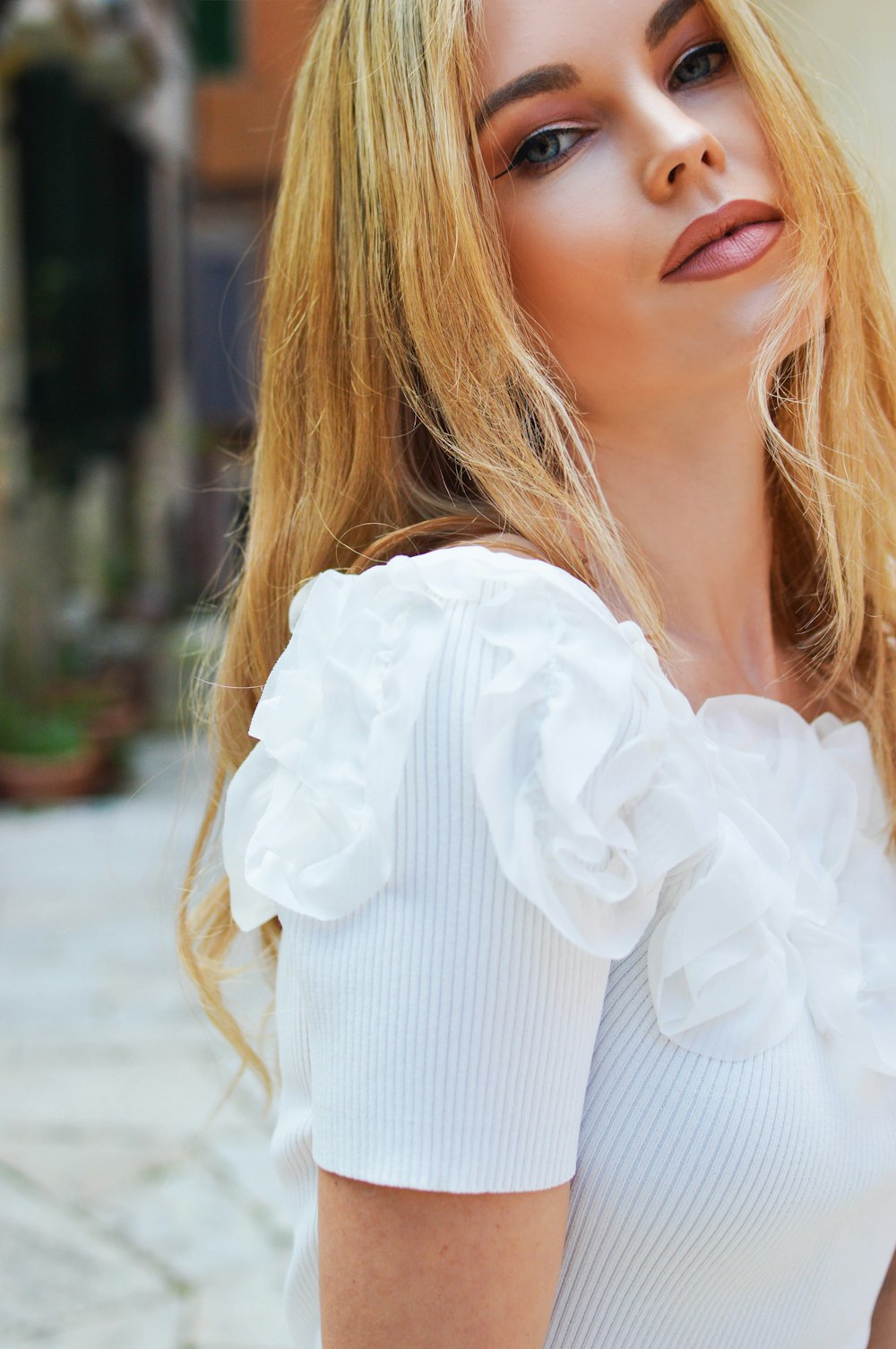 a woman with long blonde hair wearing a white top