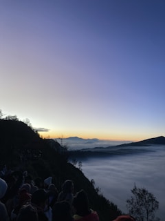 A scenic view of a mountain summit with attendees enjoying the sunrise.