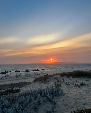 A serene Caribbean beach at sunset with soft waves and a minimalist luxury resort in the background.