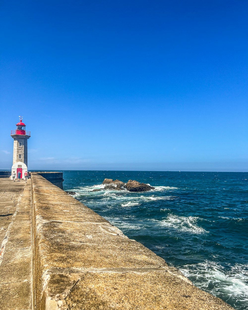 a light house sitting on top of a pier next to the ocean