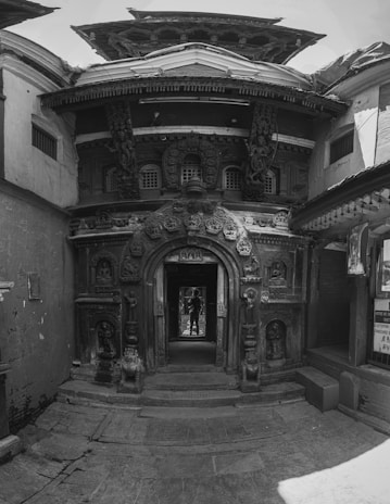 A traditional wooden entranceway featuring intricate joinery and seasonal plants outside.