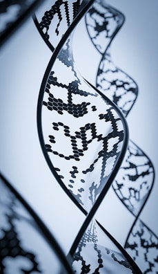 A close-up view of a stylized DNA helix with a digital and futuristic design, featuring intricate patterns and hexagonal shapes within the strands. The image has a monochromatic blue color scheme, emphasizing a modern, scientific aesthetic.
