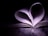 A book with its pages curved inward, forming the shape of a heart. The surrounding is dark, while the pages are illuminated by soft light, emphasizing the heart shape.