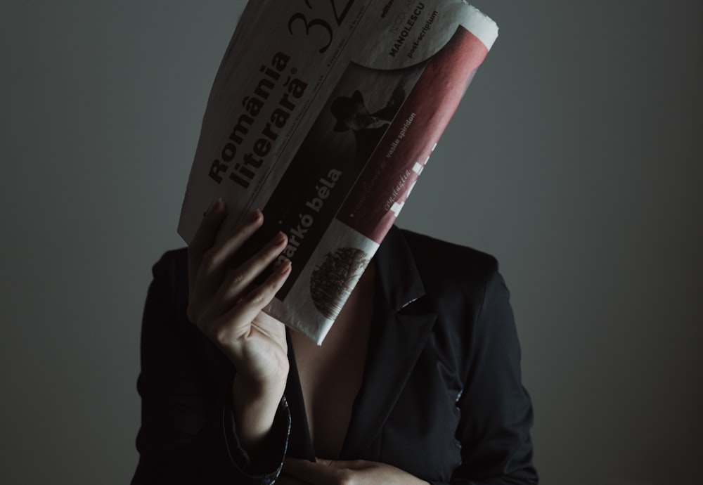 a woman in a suit holding up a newspaper