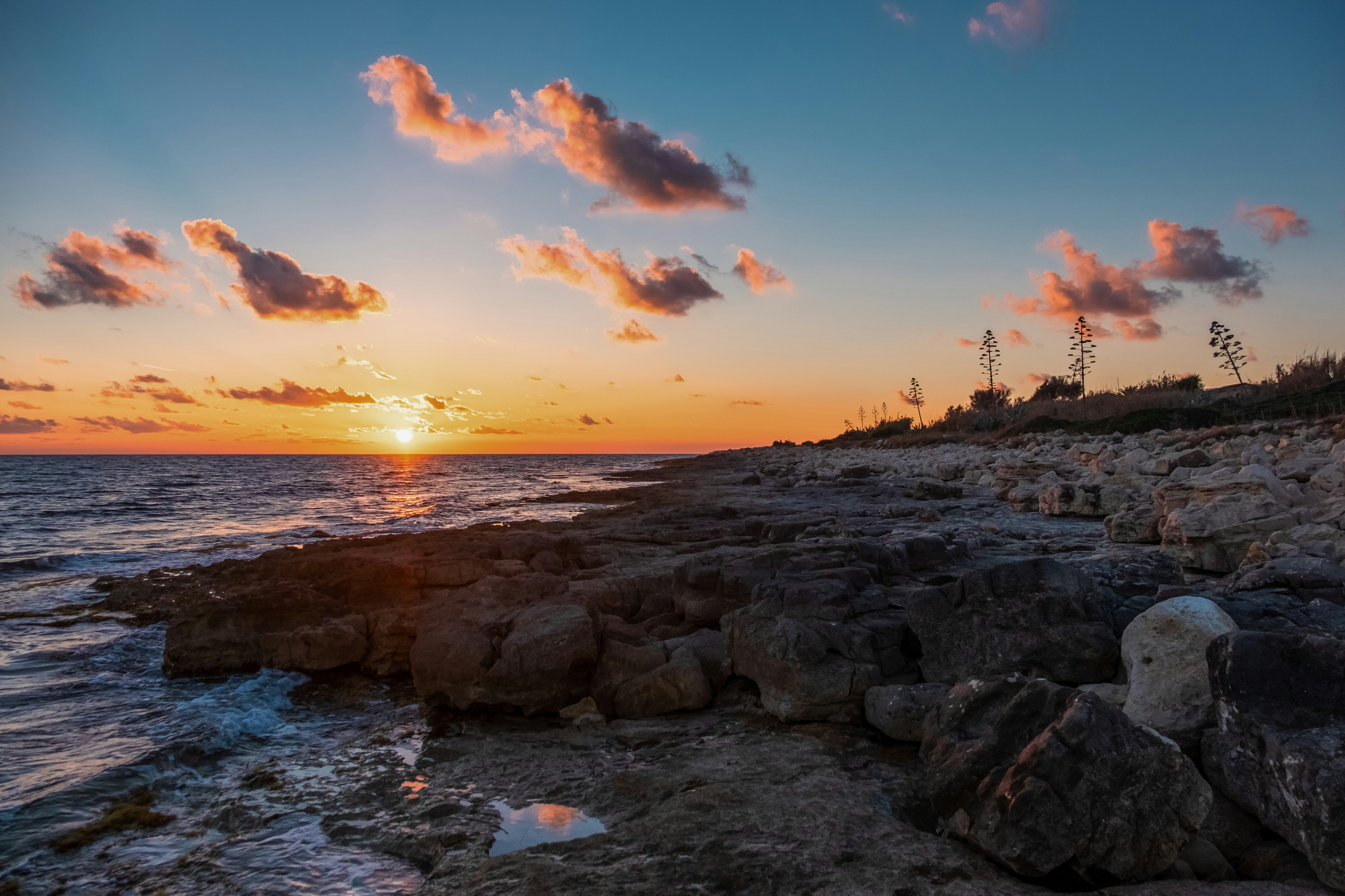 the sun is setting over a rocky shore