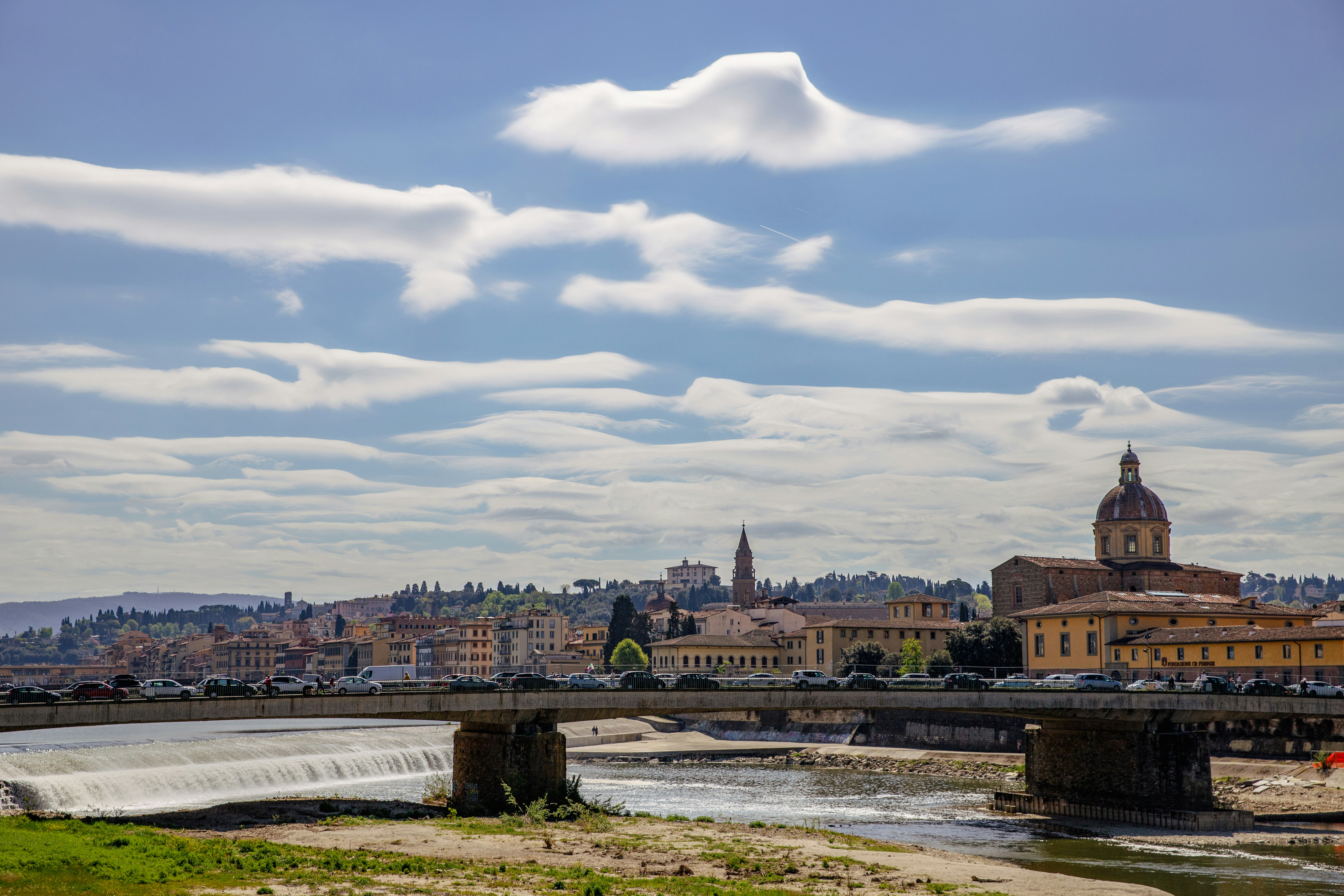 a river running through a city next to a bridge, Florence Landscape and Wonderful Clouds