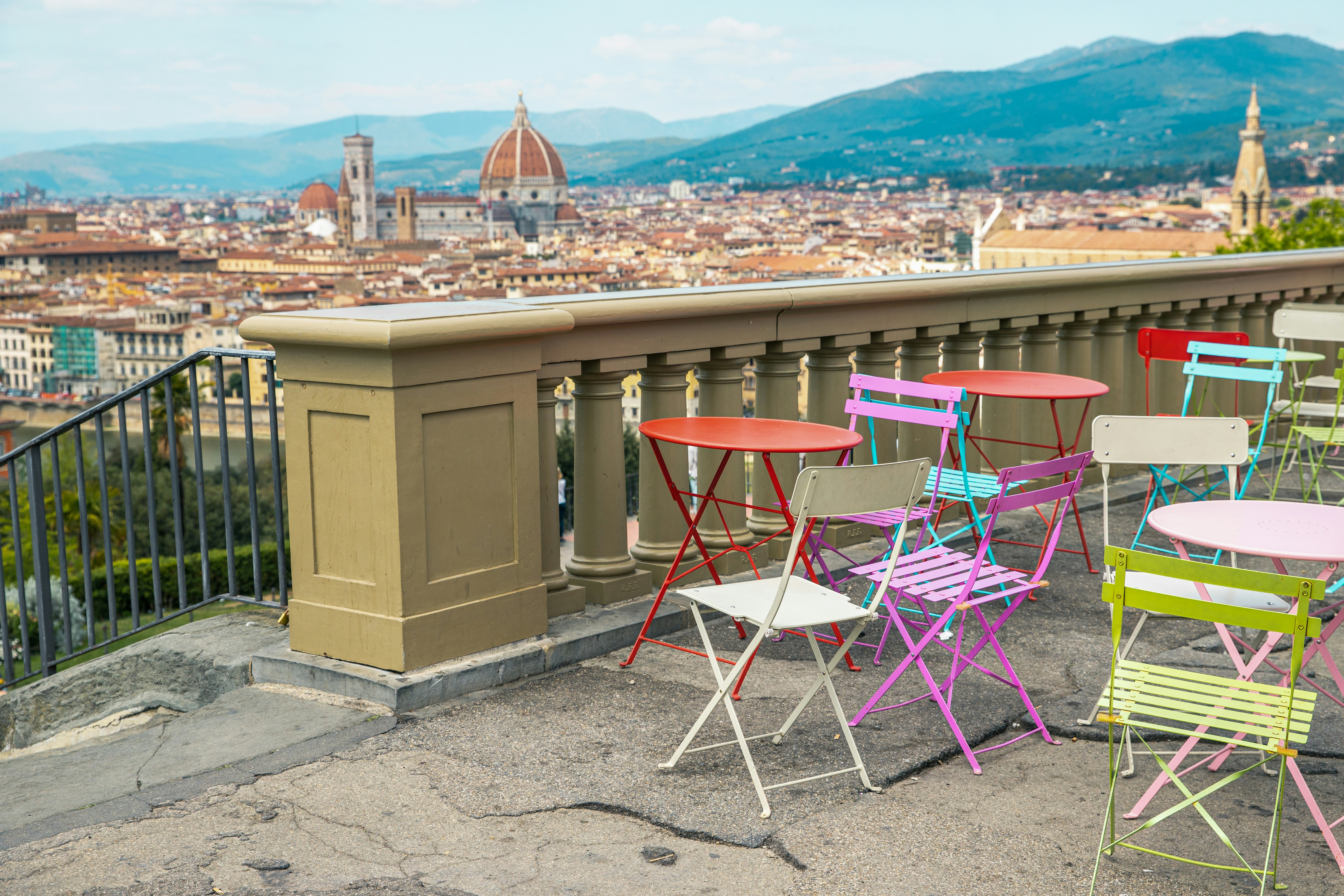 Colorful chairs and tables on a balcony overlooking a city
