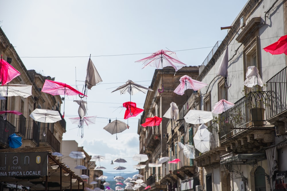 Una calle de la ciudad llena de muchos paraguas rosas y blancos