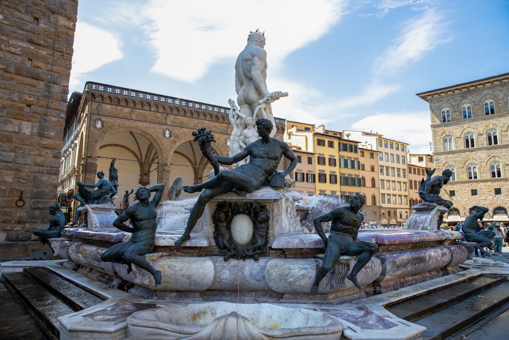 a fountain with statues on it in a city square