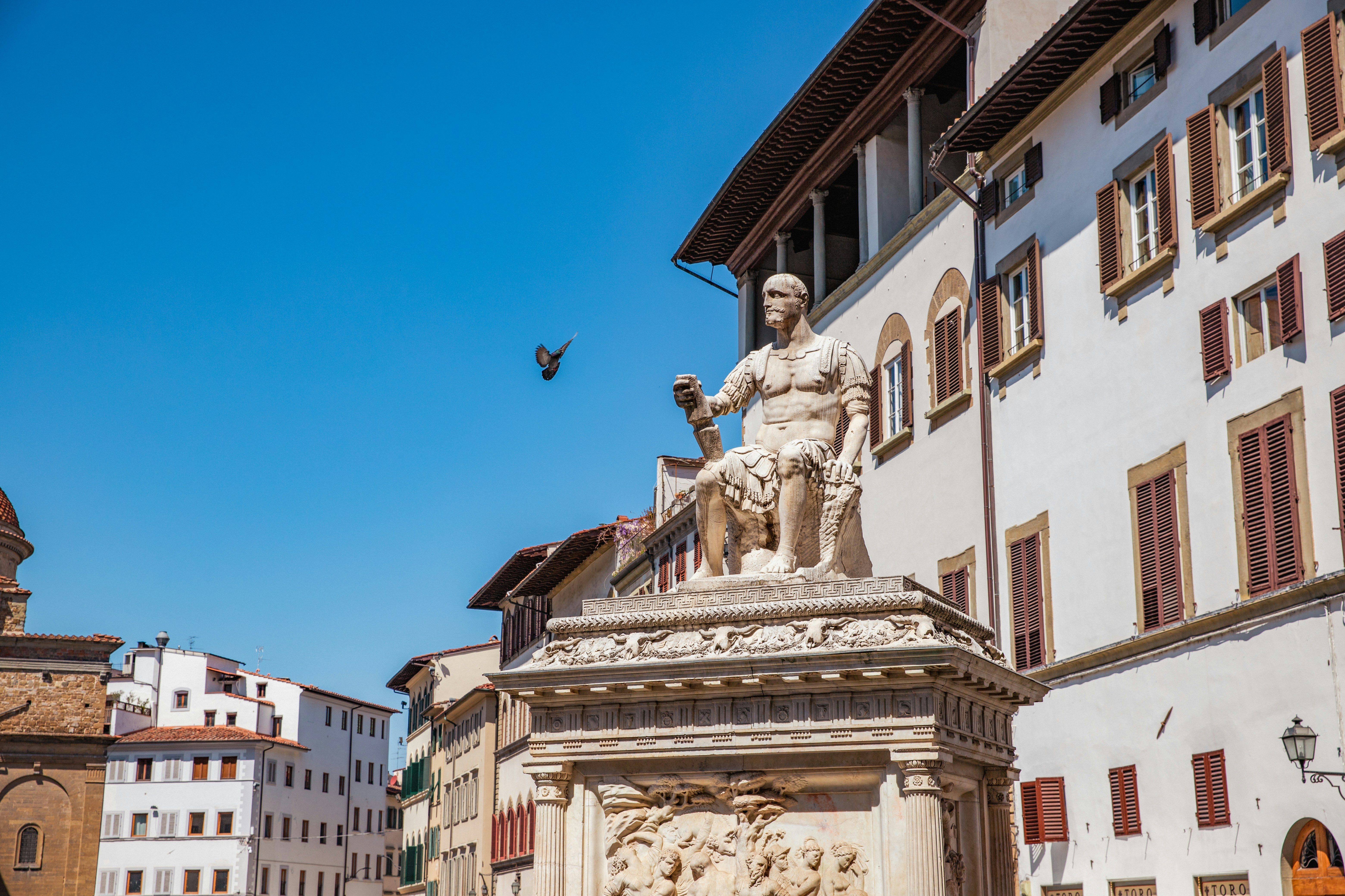 A statue of a man holding a bird in front of a building