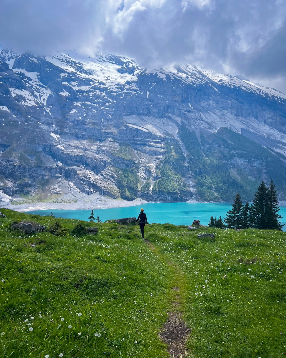 a person walking up a grassy hill towards a lake