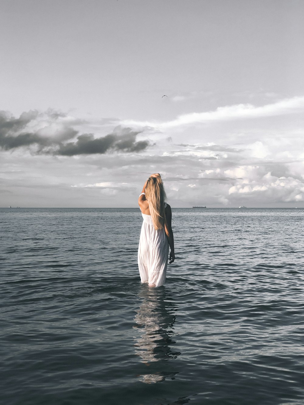 a woman standing in the water looking up at the sky