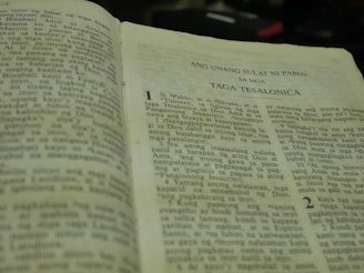 An open book written in Tagalog, specifically a religious text. The visible text mentions 'Ang Unang Sulat Ni Pablo' and 'Taga Tesalonica.' The book is slightly worn, suggesting frequent use.