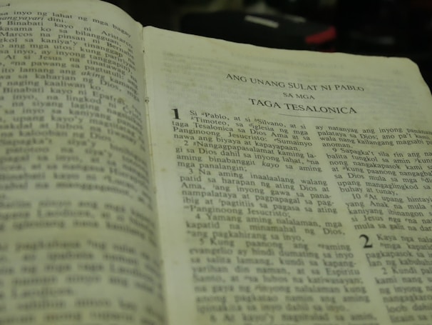 An open book written in Tagalog, specifically a religious text. The visible text mentions 'Ang Unang Sulat Ni Pablo' and 'Taga Tesalonica.' The book is slightly worn, suggesting frequent use.