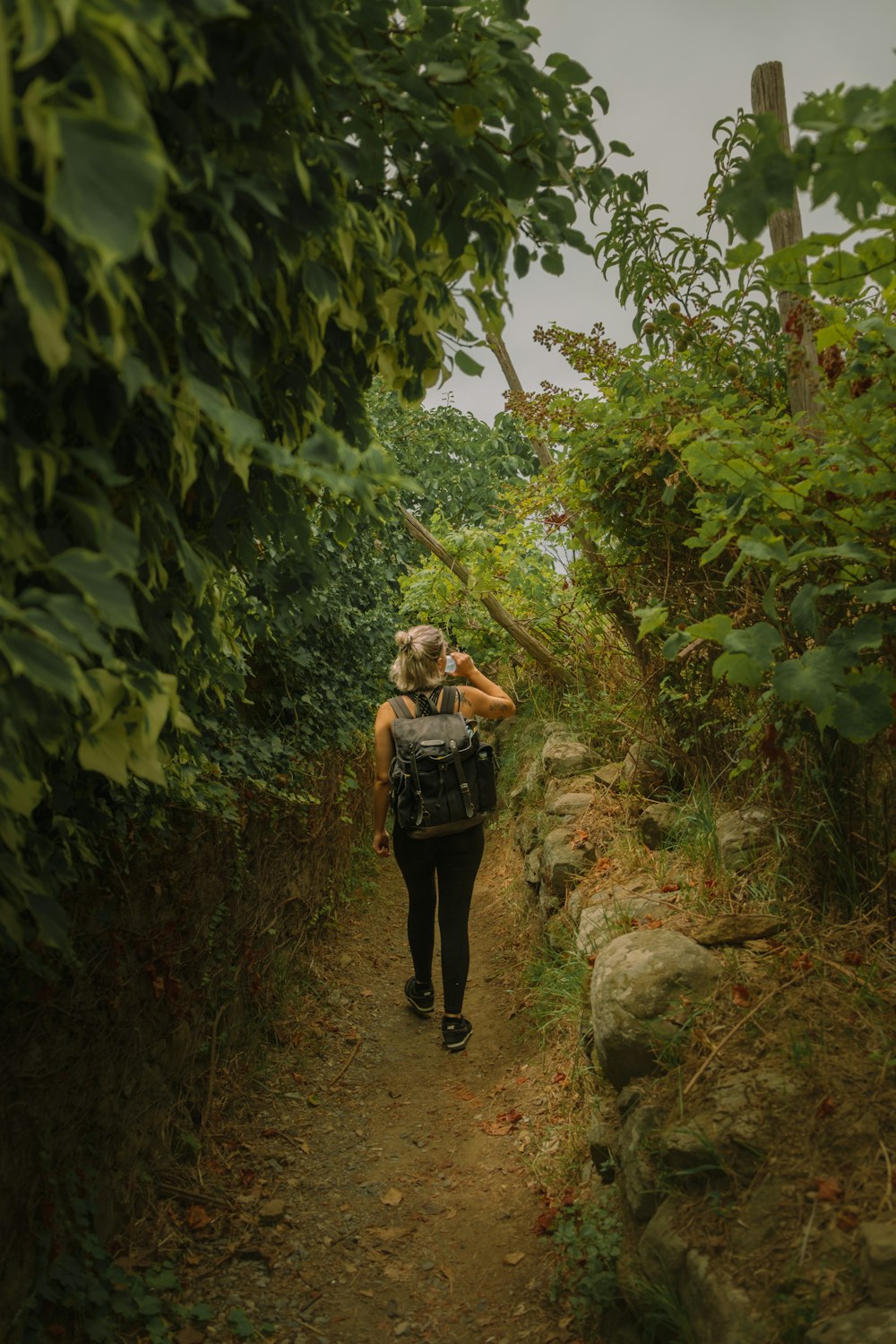 a woman with a backpack walking down a dirt path