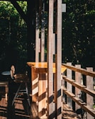 Sunlight filtering through leaves onto a rustic wooden table with macramé jewelry pieces.