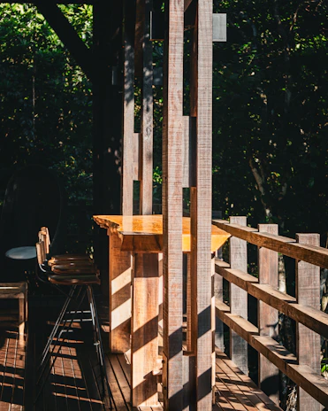 Sunlight filtering through forest leaves onto a charming chalet porch with rustic furniture.