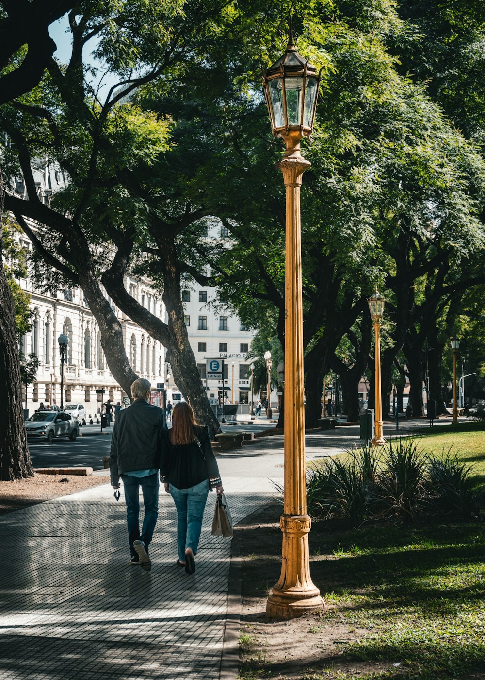 a couple of people walking down a street next to a lamp post