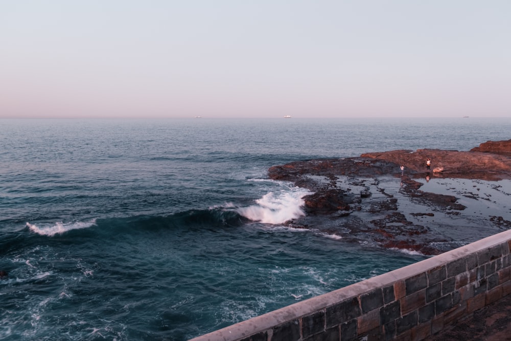 a person standing on a ledge looking out at the ocean