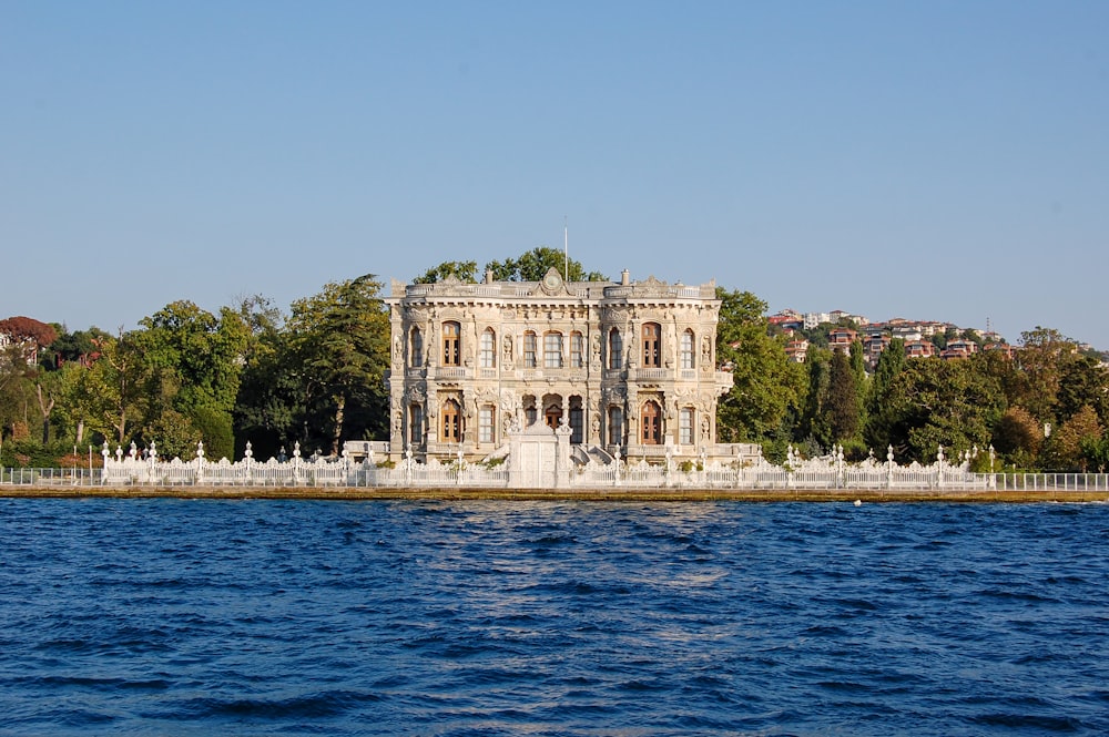 a large building sitting on top of a lake next to a forest