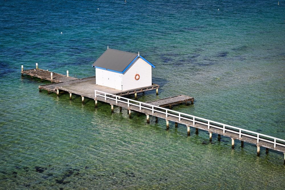 a white house sitting on top of a pier next to the ocean