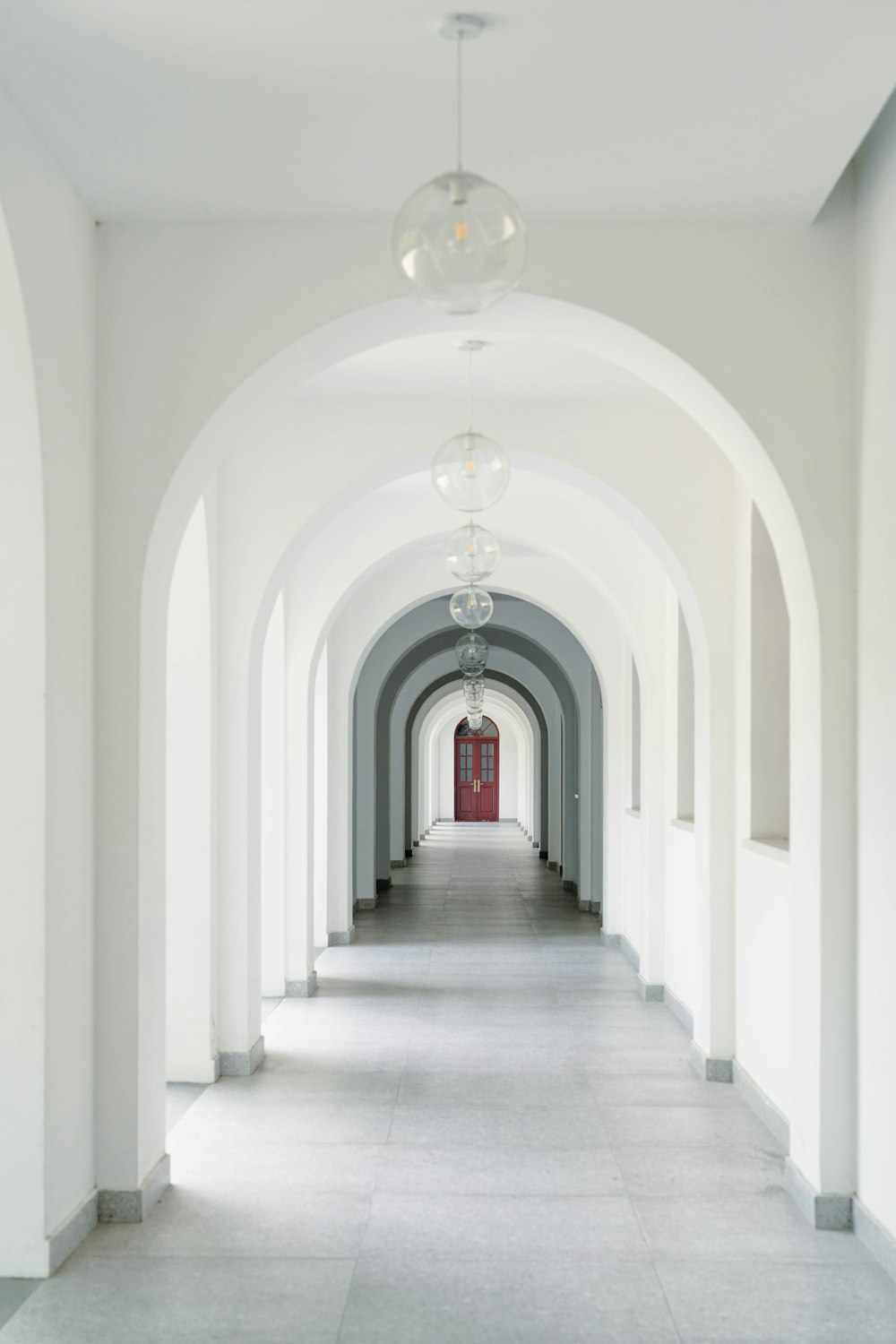 a long hallway with a red door and white walls