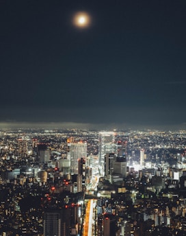 A vibrant cityscape at night with neon lights and a mysterious moonlit sky.