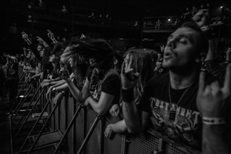 A close-up shot of a roaring crowd at a heavy metal concert, fists raised and lights flashing.