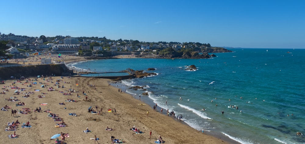 a beach filled with lots of people on a sunny day