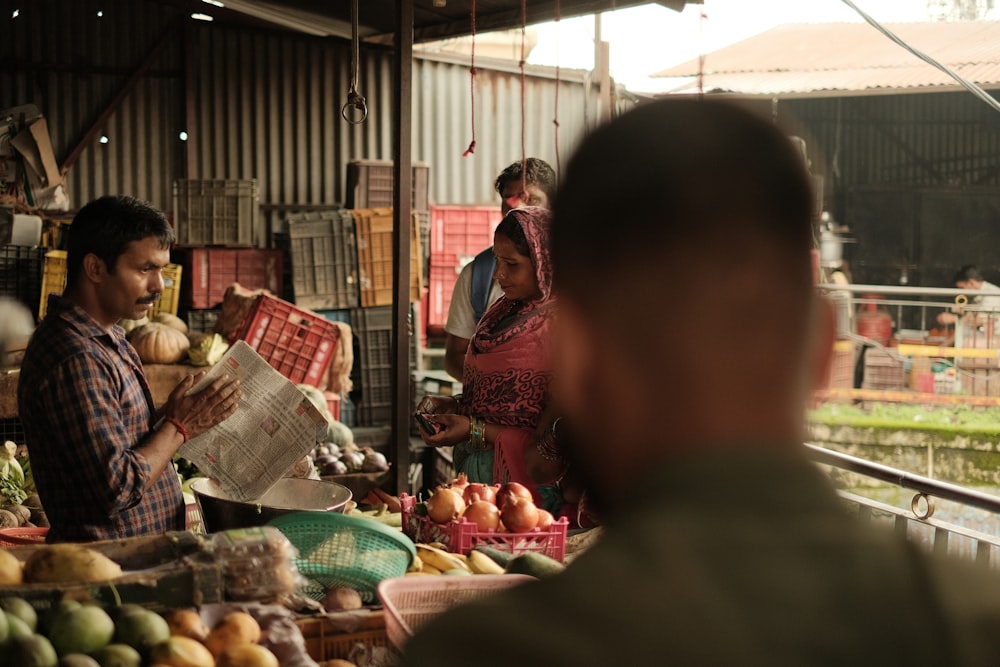 a group of people standing around a fruit stand