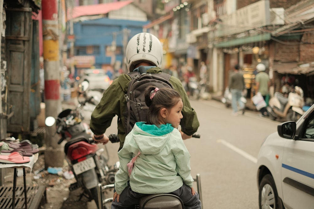 a man riding a motorcycle with a little girl on the back of it