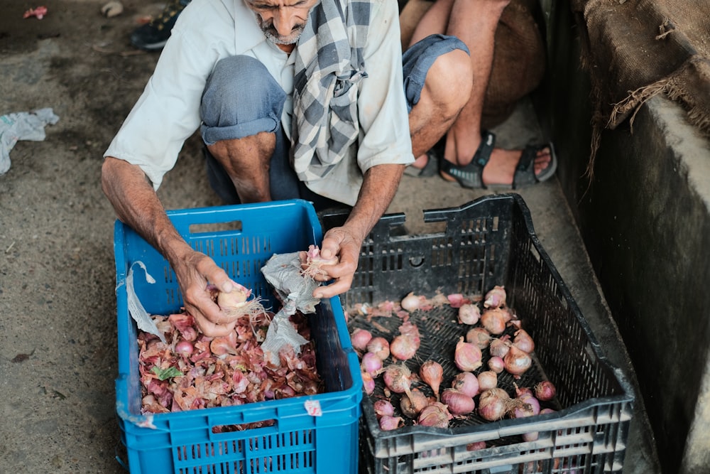 a man is picking up onions from a crate