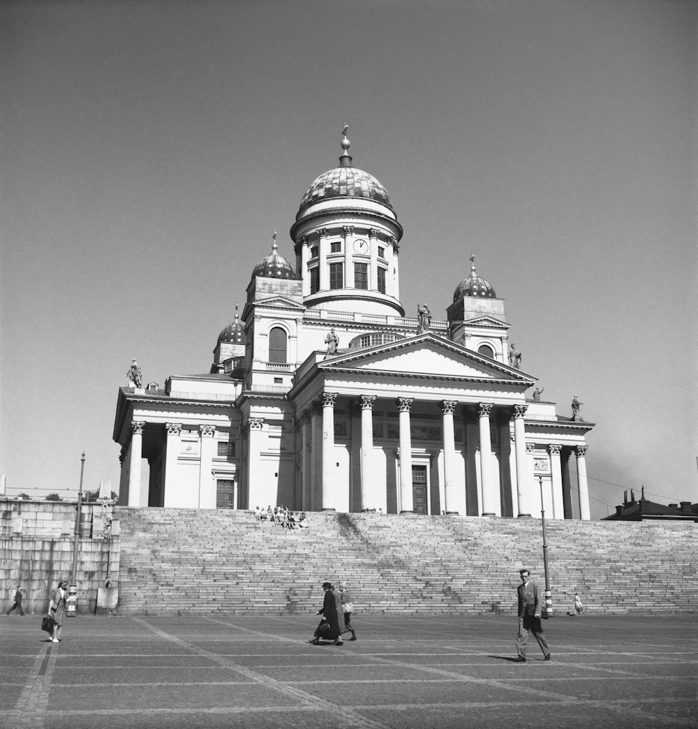 a black and white photo of people walking in front of a building