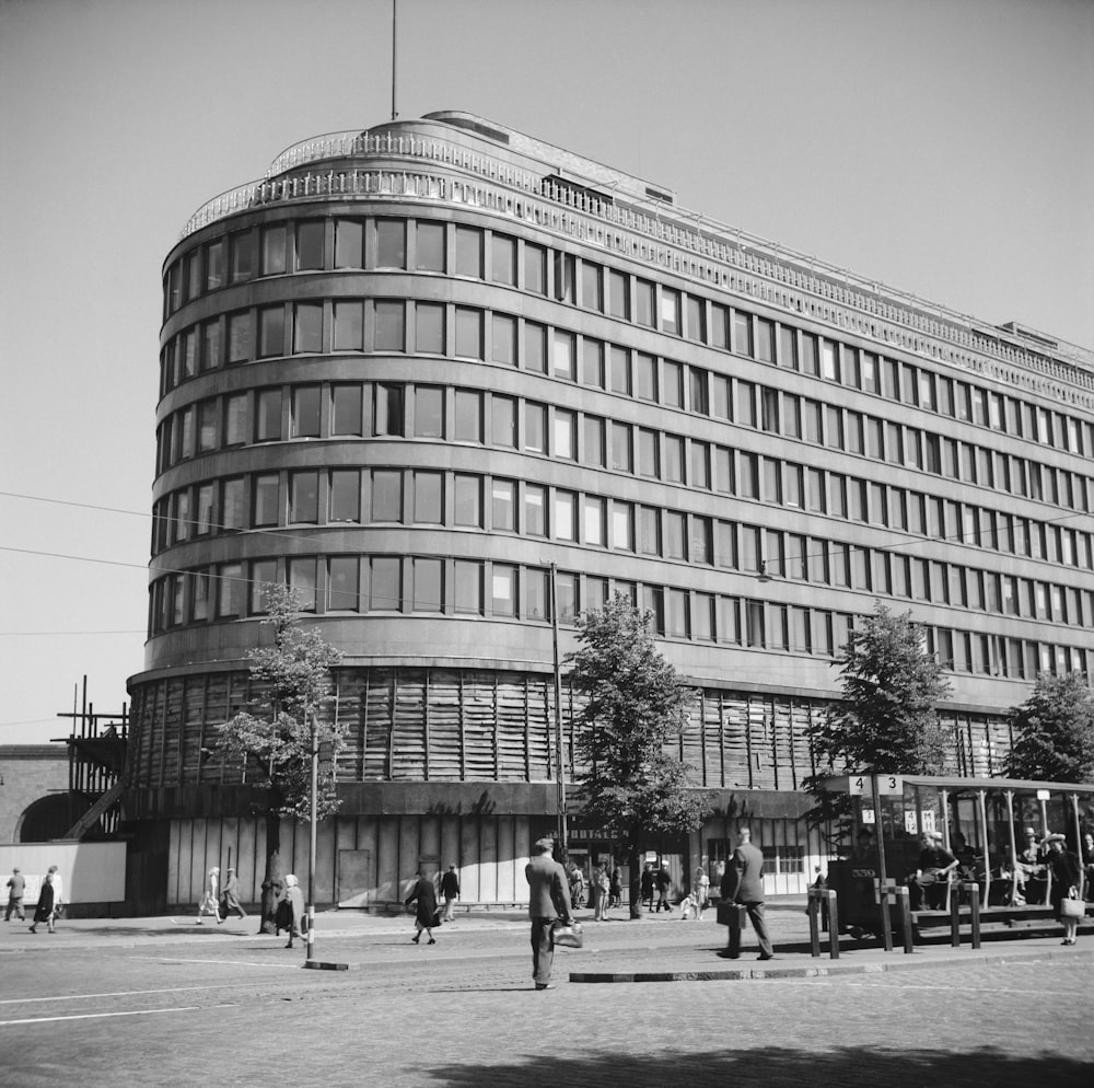 건물 앞을 걷고 있는 사람들의 흑백 사진