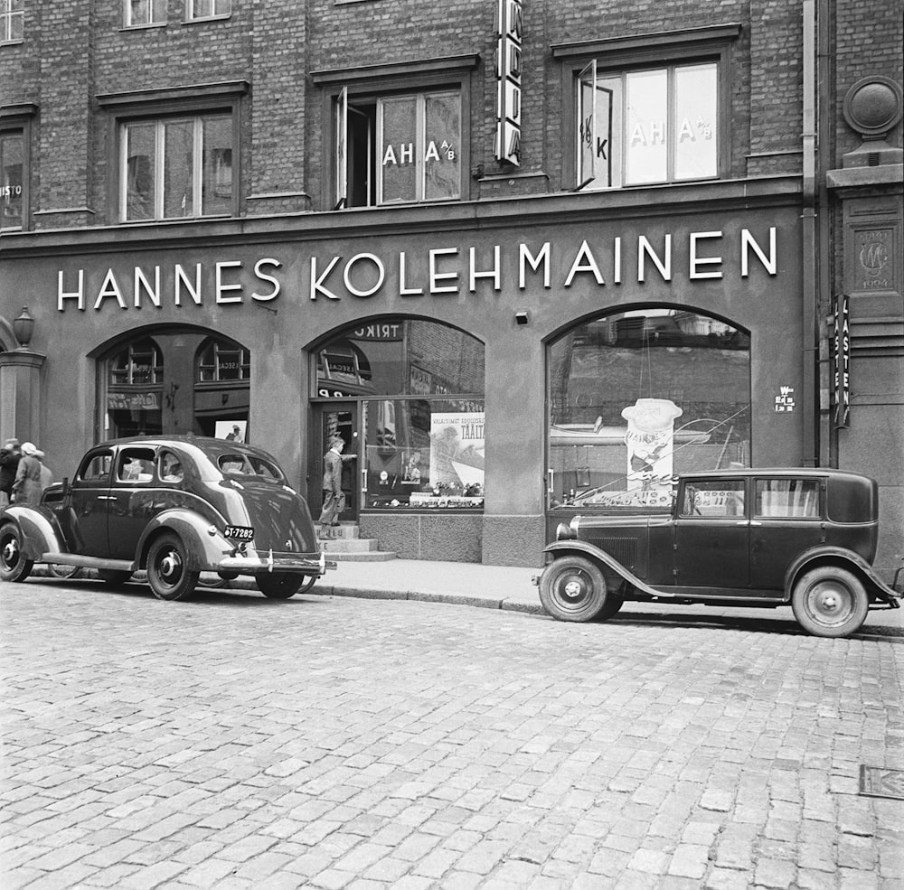 a vintage photo of an old car parked in front of a store