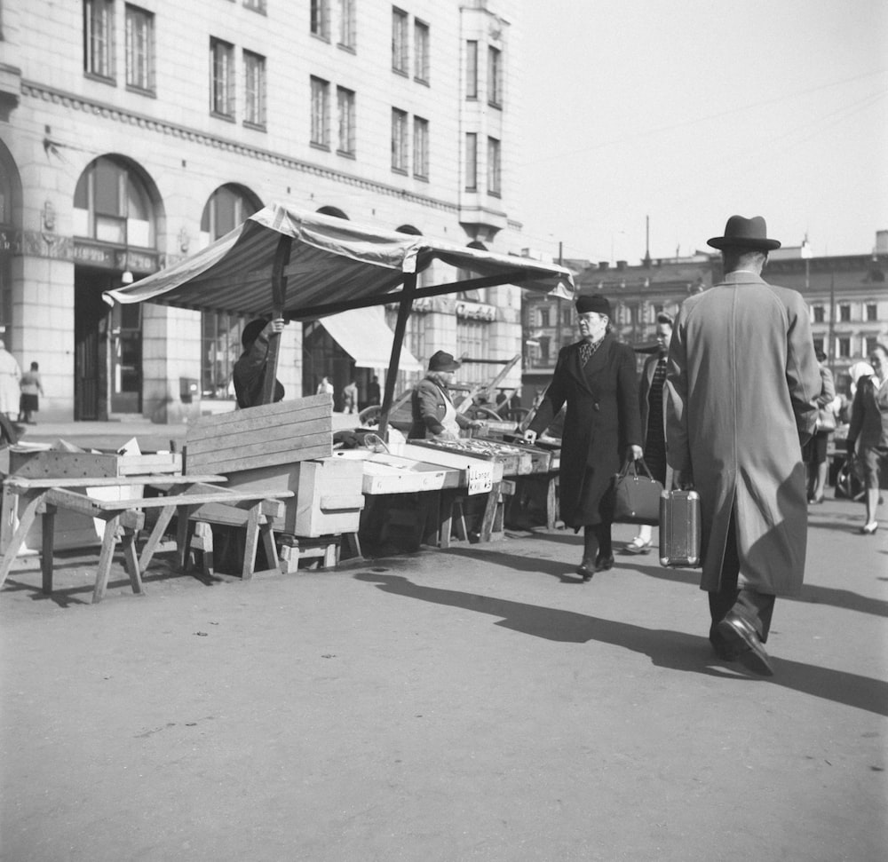 a black and white photo of people walking around a market