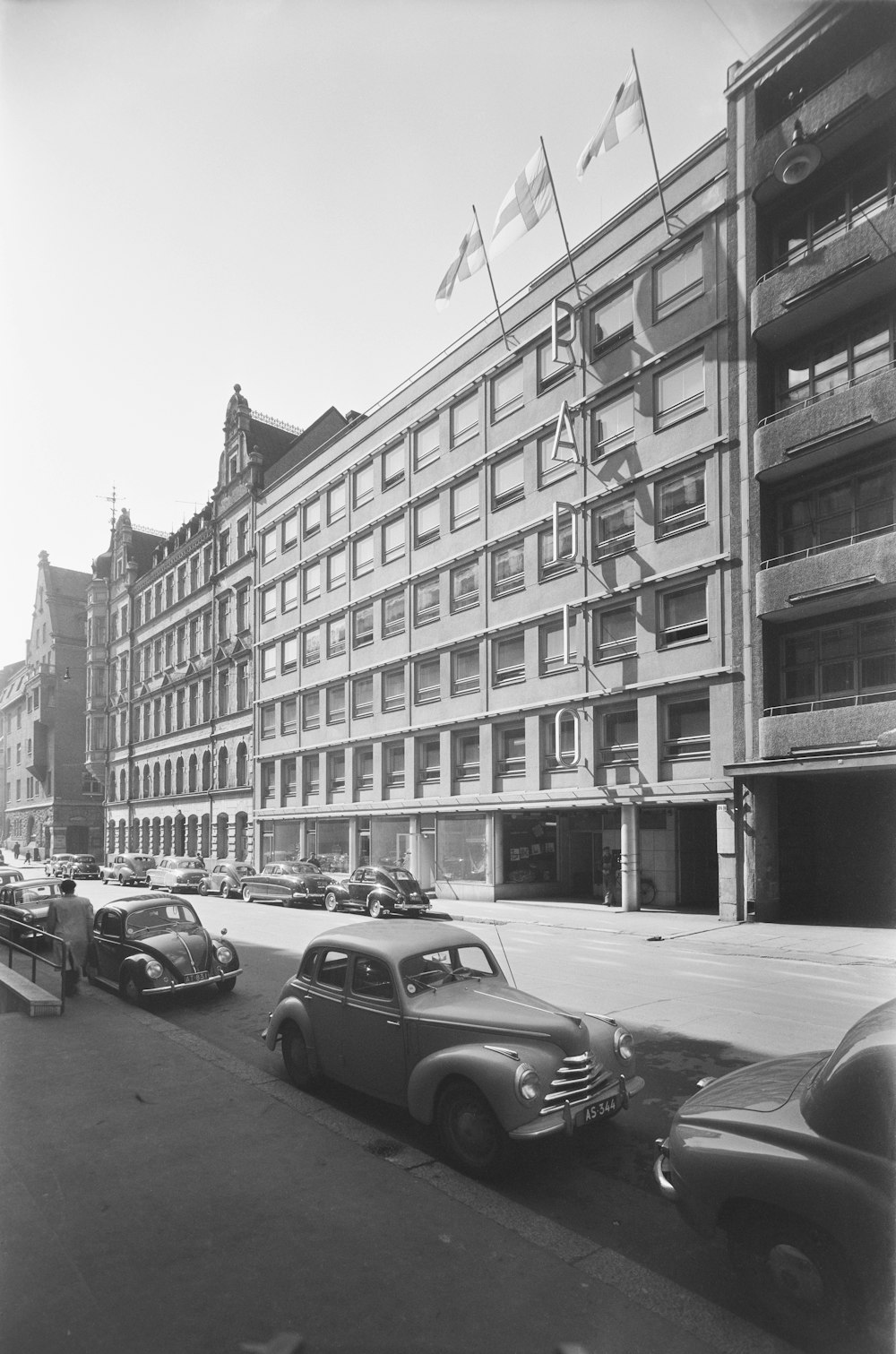 a black and white photo of cars parked in front of a building