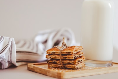 A rustic wooden table with a fresh batch of golden cookies cooling beside a soft cream linen.