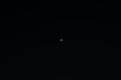 A small, distant celestial object, likely the moon, is visible against a vast, black sky. The minimalistic composition emphasizes the isolation and quietness of space.