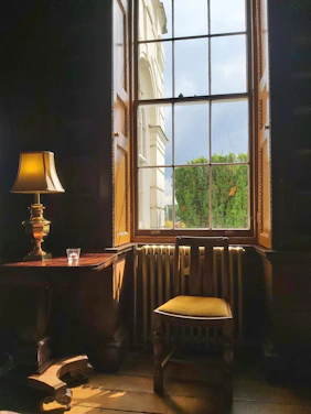 A calm, softly lit room with a comfortable chair and warm natural light streaming through a window.